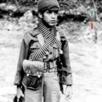 An image of a young Iranian child in army uniform carrying a weapon.