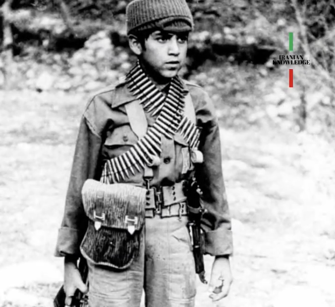 An image of a young Iranian child in army uniform carrying a weapon.